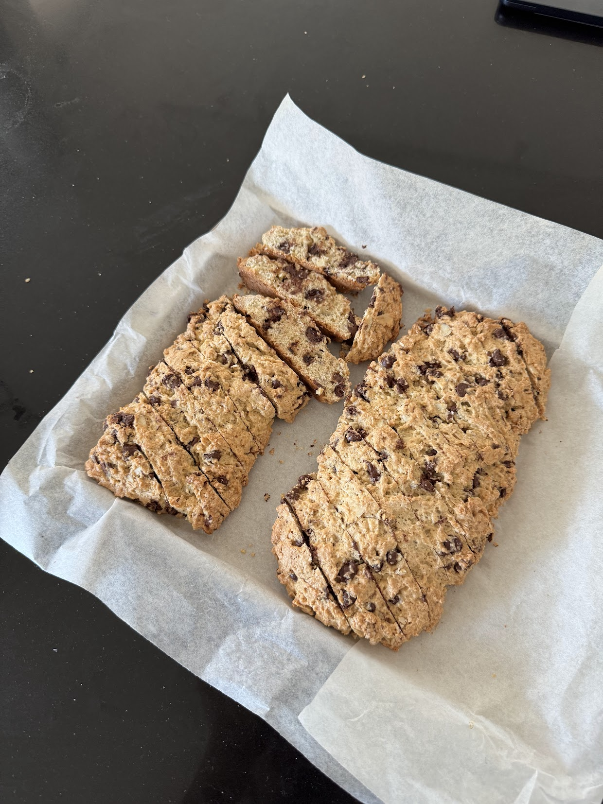 Biscotti logs sliced diagonally on parchment paper, ready for the second bake
